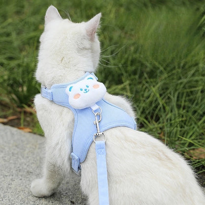Chat blanc portant un harnais bleu décoré d'un ourson